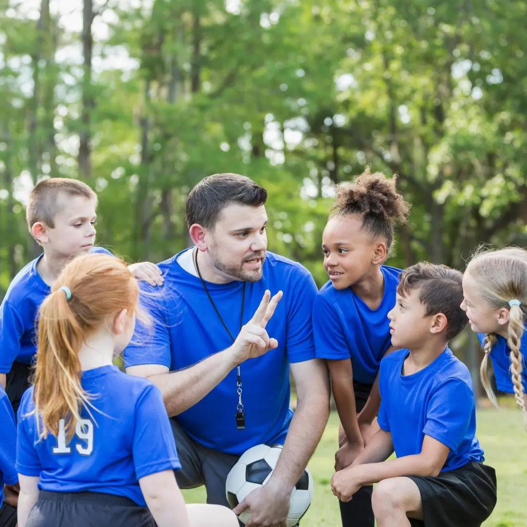 Youth soccer team gathered on the field with their coach