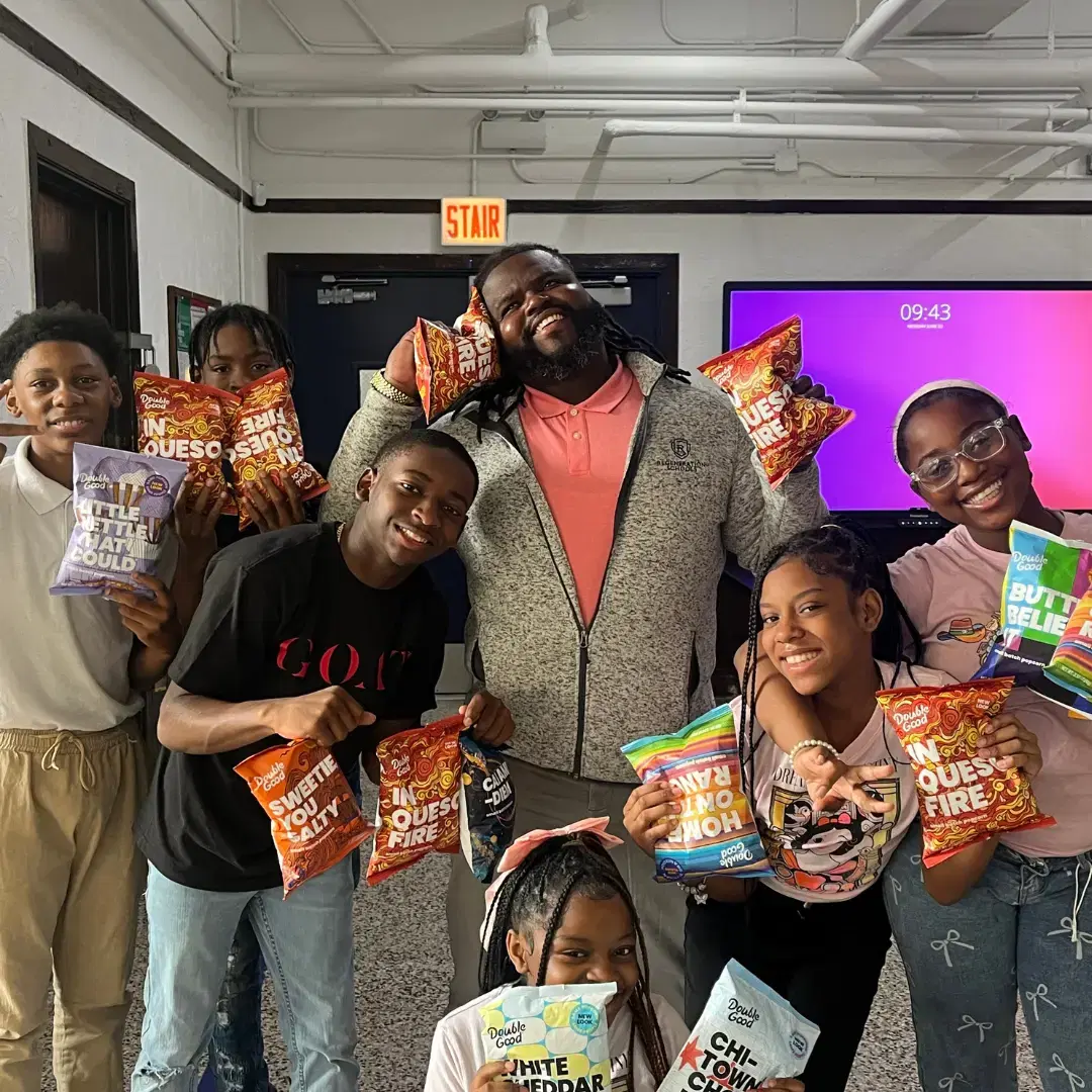 Students and a school leader smile while holding popcorn bags in a fundraiser for school success story.
