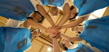 Group of girls basketball all putting their hands in the middle