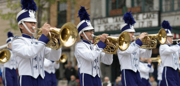 Brass section marching in a parade during high school band fundraiser season