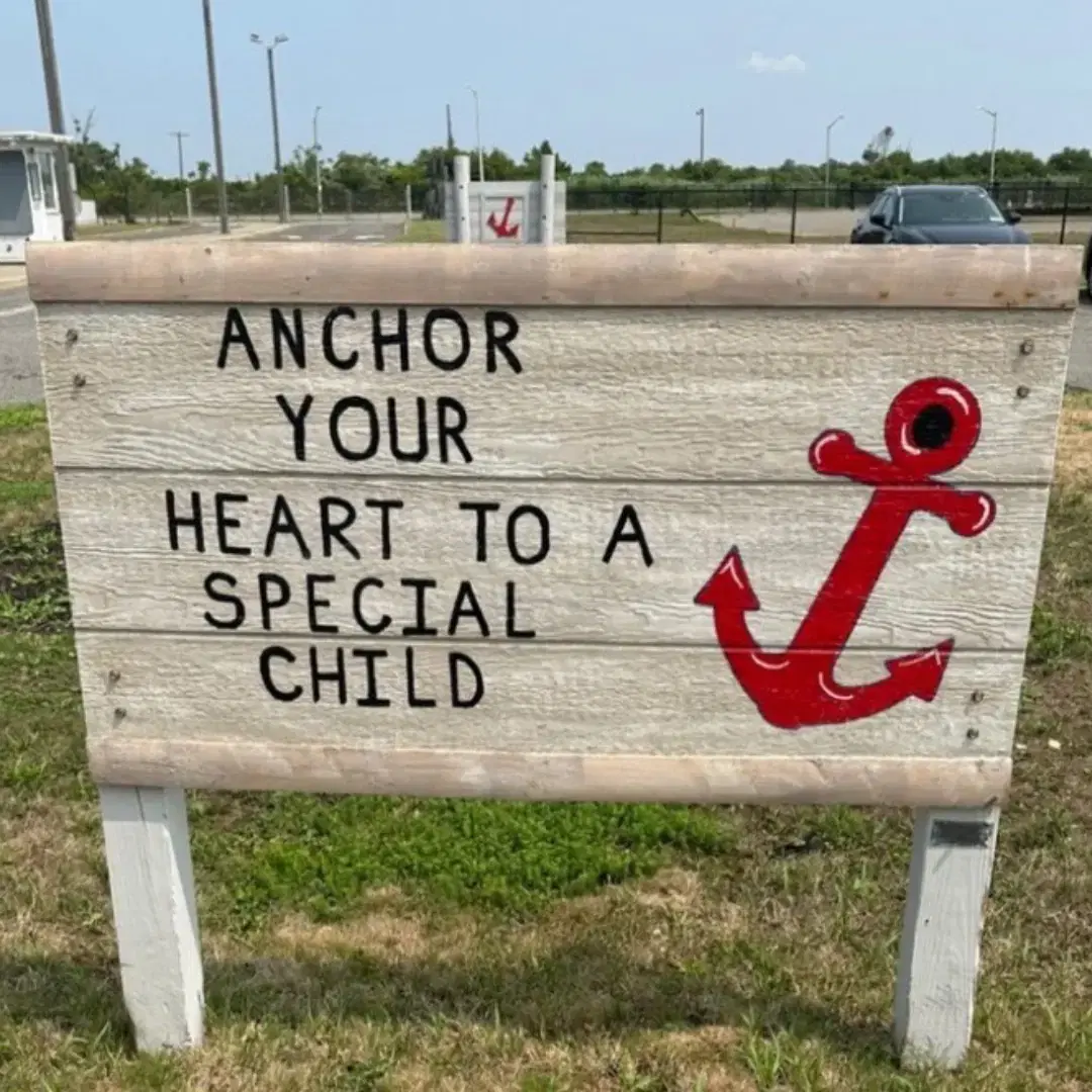 Wooden sign with text "ANCHOR YOUR HEART TO A SPECIAL CHILD" alongside a red anchor symbol.