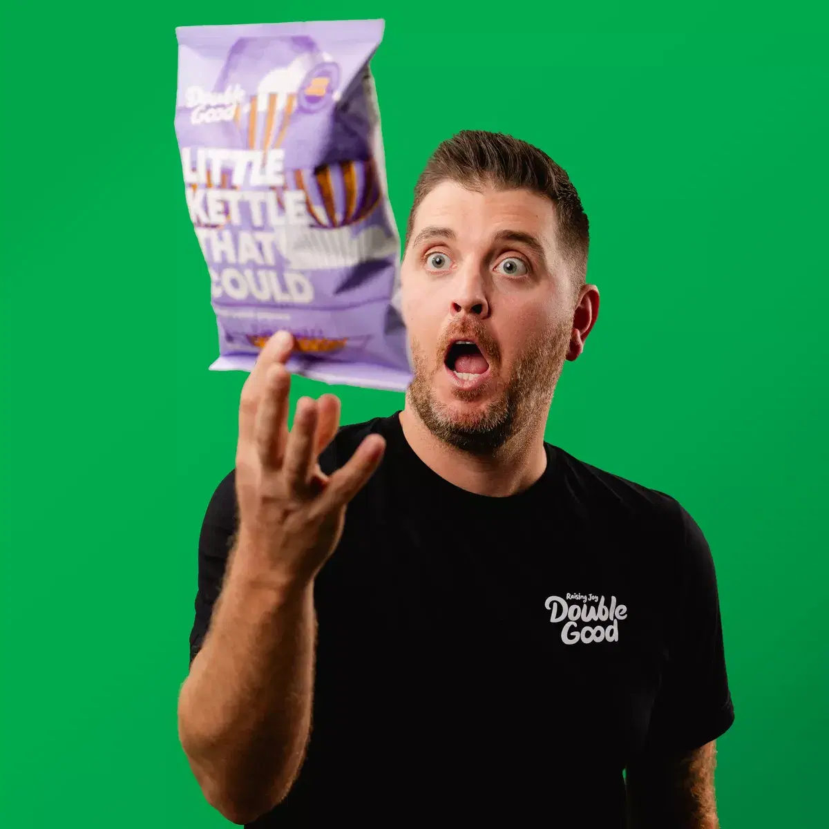 Dan is balancing a bag of popcorn on his finger and is expressing shock and amazement with his face.