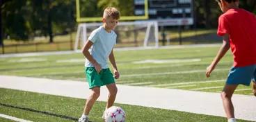 Two kids playing soccer, featured on a soccer fundraising landing page